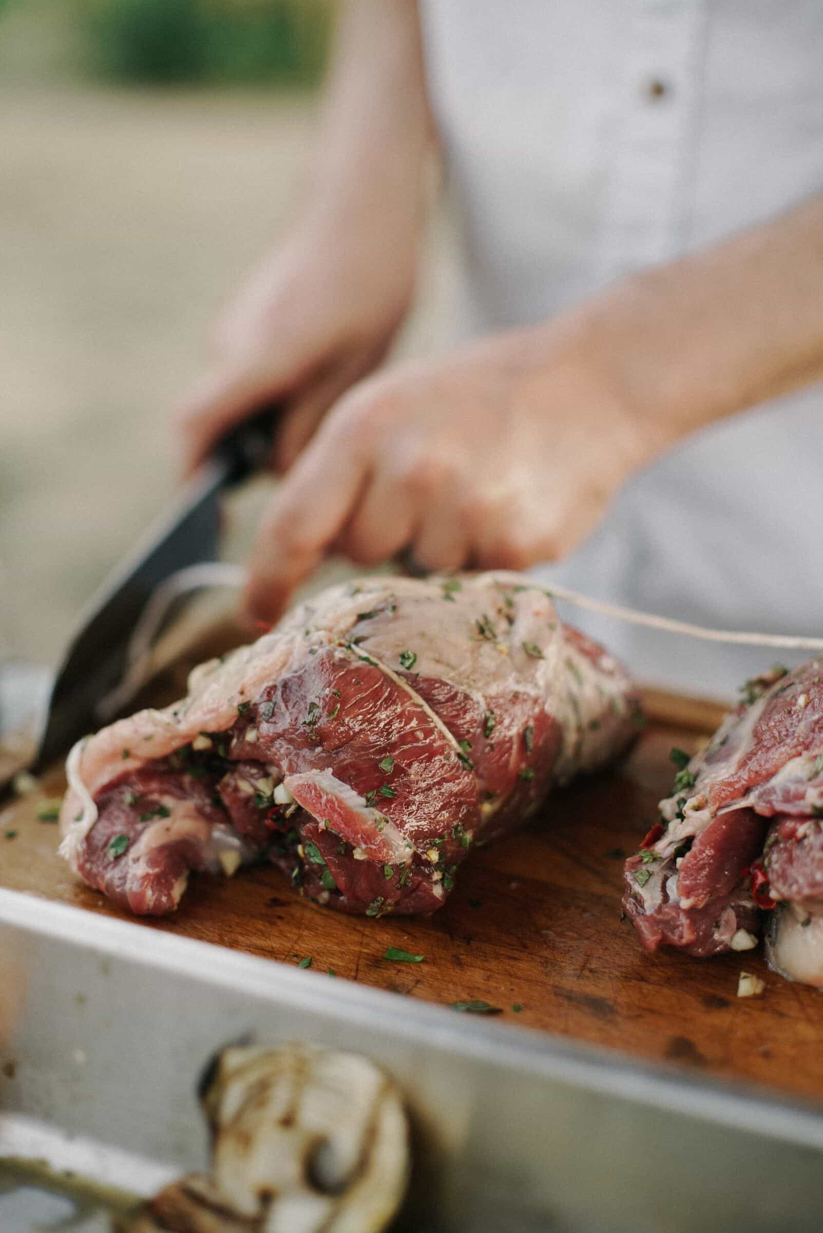a chef is cutting the grilled meat with a knife