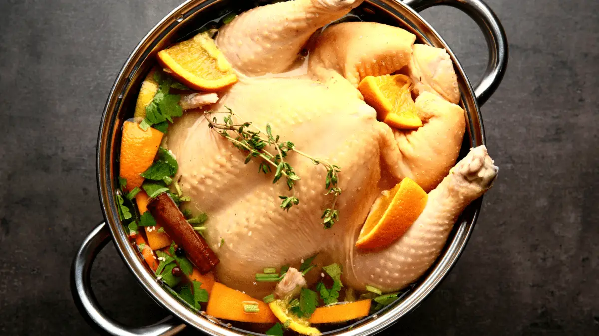 brined whole chicken in a pot with herbs