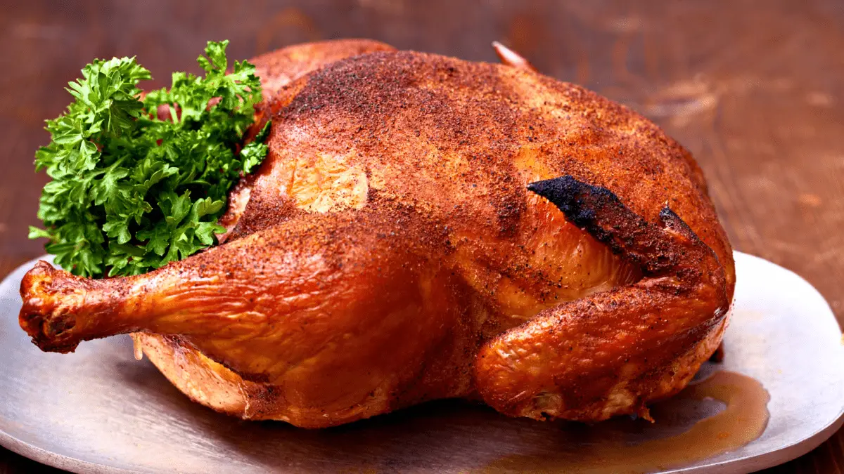 whole smoked chicken on a carving board with herbs