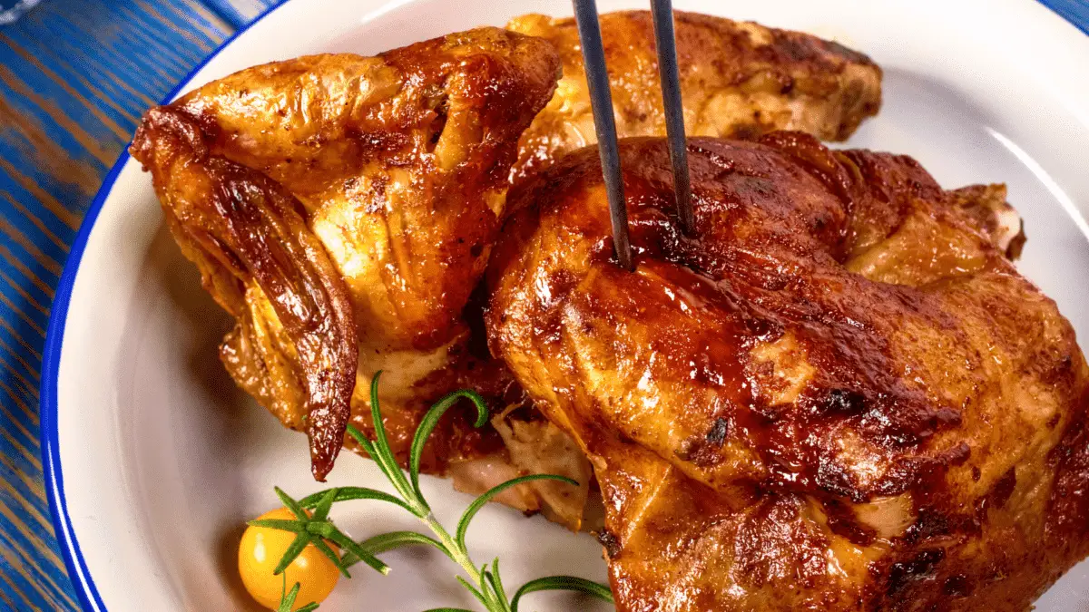 smoked chicken quarter on a plate with lemon wedge and herbs