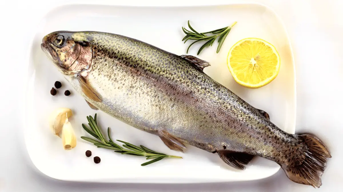 whole trout on a platter with surrounding herbs